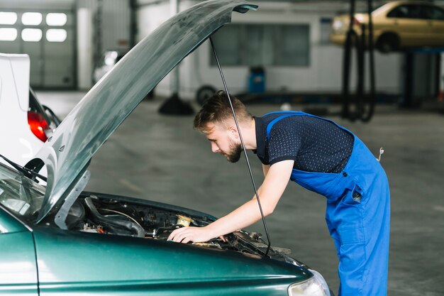 Técnico que repara el motor del coche en el garaje