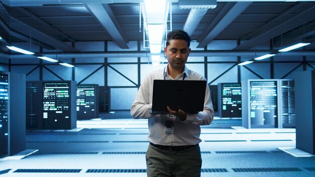 Técnico que utiliza una computadora portátil en el centro de datos que administra los servidores