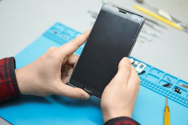 Técnico sosteniendo un teléfono inteligente, va a eliminar las burbujas de aire en vidrio templado fijo en el gadget