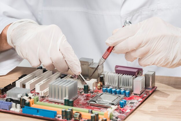 Técnico usando guantes trabajando en computadora placa base