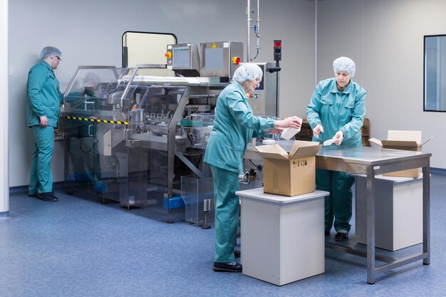 Técnicos farmacéuticos trabajan en condiciones de trabajo estériles en una fábrica farmacéutica Científicos que usan ropa protectora