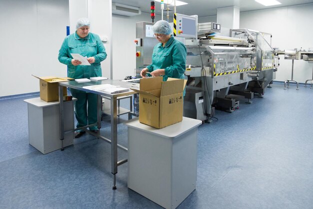 Técnicos farmacéuticos trabajan en condiciones de trabajo estériles en una fábrica farmacéutica Científicos que usan ropa protectora