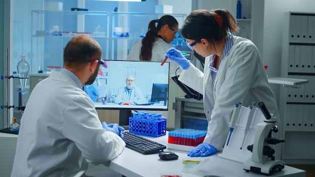 Foto gratuita técnicos de laboratorio hablando por videollamada con el médico químico profesional explicando las reacciones a la vacuna