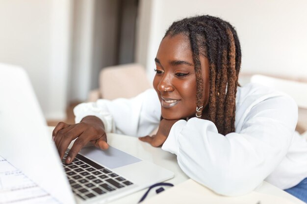 Tecnología de trabajo remoto y concepto de personas joven mujer de negocios africana con computadora portátil y papeles que trabajan en la oficina en casa durante la crisis de salud de Covid19