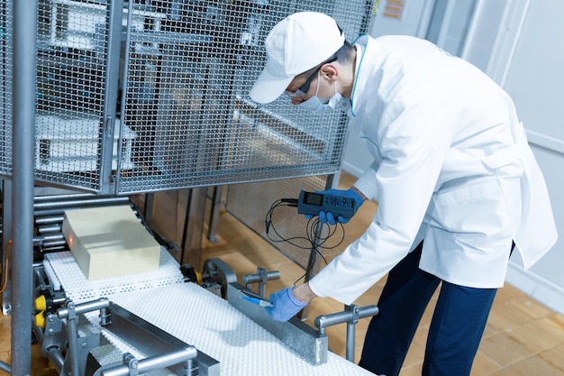 Foto gratuita el tecnólogo configura la línea de producción mientras se encuentra cerca de la pantalla digital en el departamento de la fábrica de productos lácteos