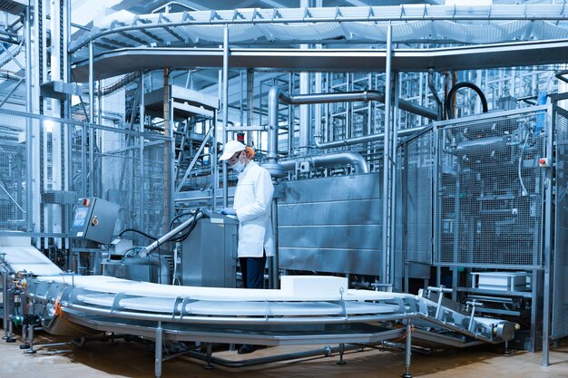 El tecnólogo configura la línea de producción mientras se encuentra cerca de la pantalla digital en el departamento de la fábrica de productos lácteos