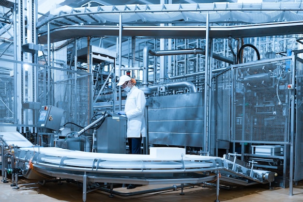 El tecnólogo configura la línea de producción mientras se encuentra cerca de la pantalla digital en el departamento de la fábrica de productos lácteos