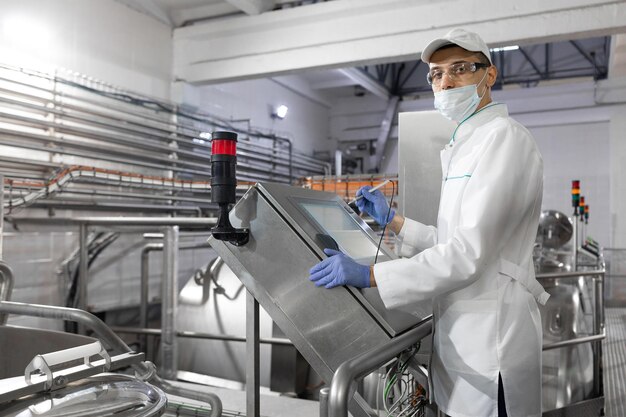 El tecnólogo configura la línea de producción mientras se encuentra cerca de la pantalla digital en el departamento de la fábrica de productos lácteos