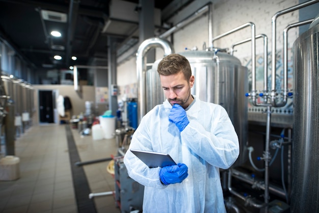 Tecnólogo leyendo informes de producción en tablet PC en la fábrica.