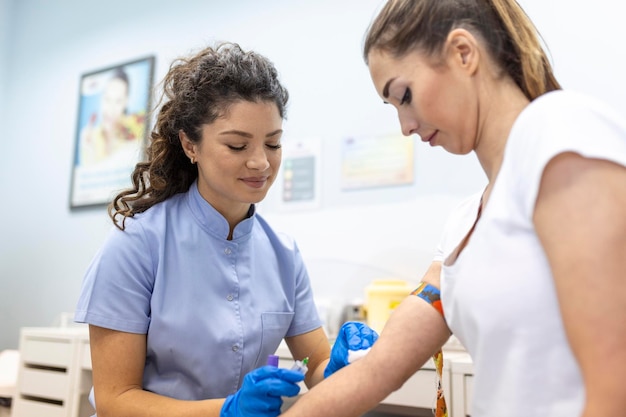 Tecnólogo médico que realiza servicios de extracción de sangre para el asistente de laboratorio del paciente con guantes de goma estériles que toman muestras de sangre del paciente