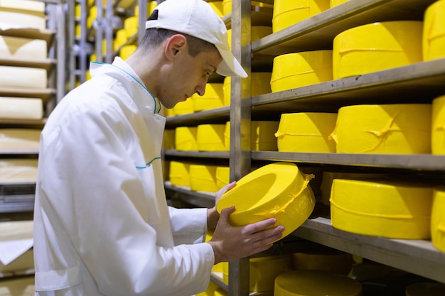 Foto gratuita el tecnólogo con queso en las manos realiza una inspección de la producción lista en el departamento de la fábrica de productos lácteos