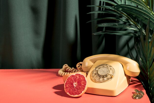 Telefono amarillo junto a pomelo sobre mesa.