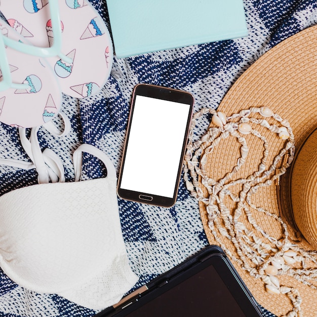 Teléfono, bikini, chanclas y sombrero sobre toalla de playa