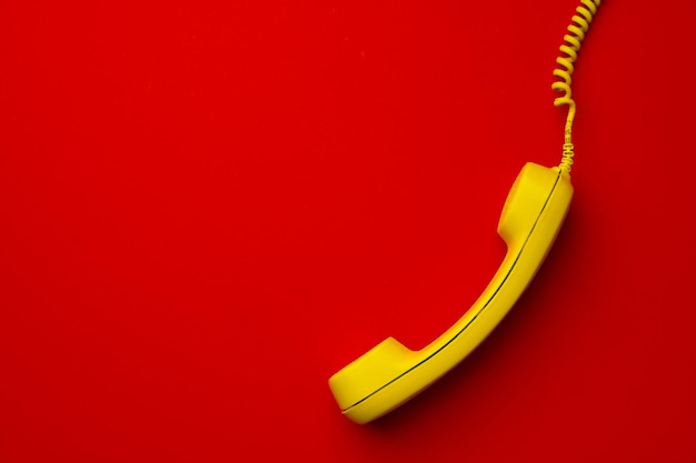 Foto gratuita teléfono fijo amarillo en la vista superior de fondo rojo