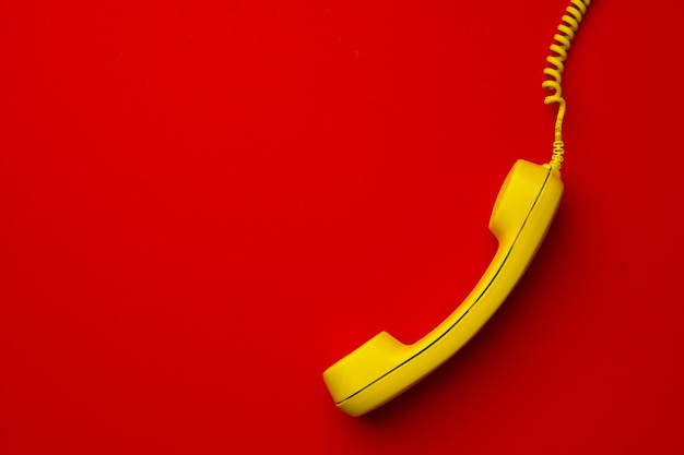 Teléfono fijo amarillo en la vista superior de fondo rojo