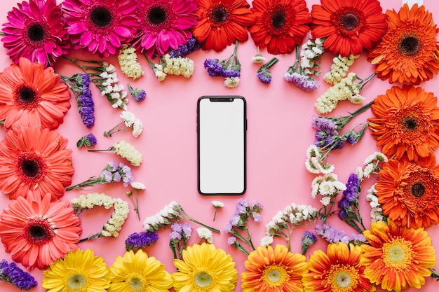 Foto gratuita teléfono inteligente de alta tecnología en coloridas flores diferentes