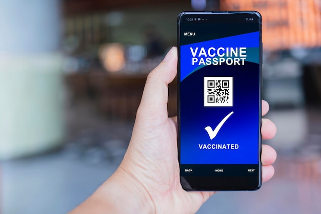 Teléfono inteligente que muestra un certificado de vacunación digital válido para COVID19 en el fondo del área pública de la mano del hombre Vacunación inmunidad a enfermedades pasaporte salud y conceptos de viaje seguros