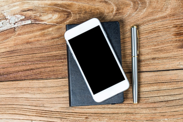 Teléfono móvil y auriculares sobre fondo de madera