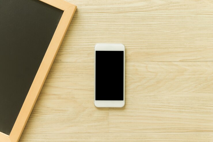 Foto gratuito teléfono móvil con pantalla en blanco y marco de pizarra de madera en blanco sobre fondo de madera de la tabla. vista superior con espacio de la copia. se puede utilizar imitación de imagen. vintage efecto estilo imágenes.