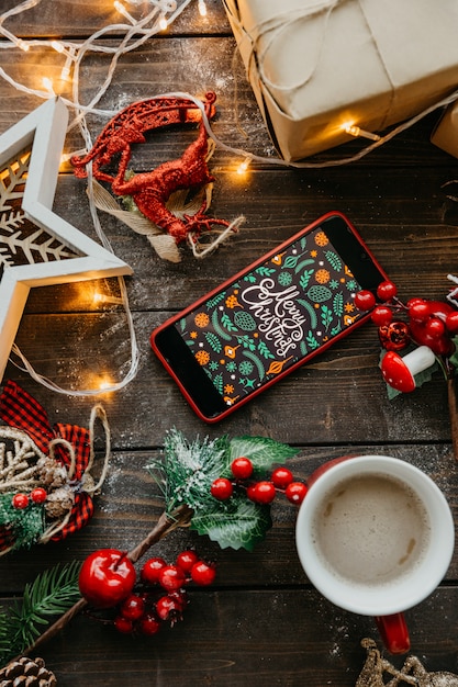 Teléfono con pantalla navideña y café con leche sobre la mesa