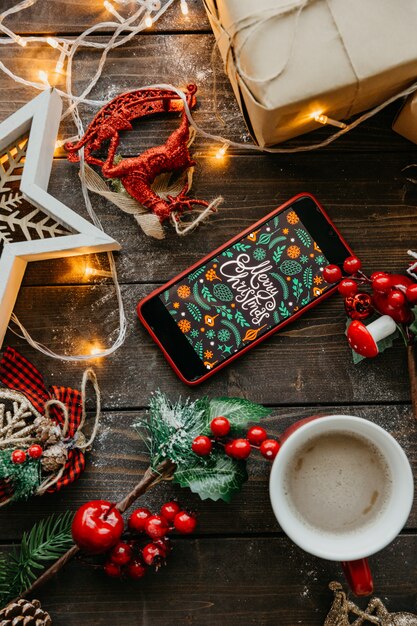 Teléfono con pantalla navideña y café con leche sobre la mesa