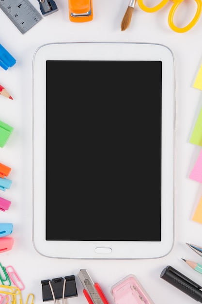 Teléfono de la tableta y herramientas de la escuela o de la oficina en el fondo blanco
