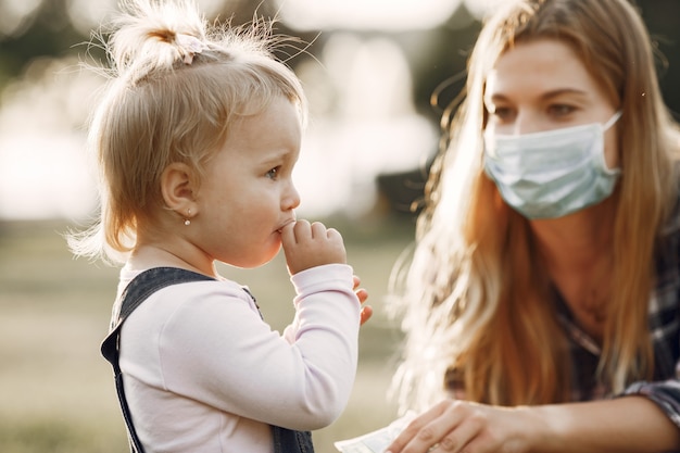 Tema de coronavirus. Familia en un parque de verano. Mujer con camisa de celda.