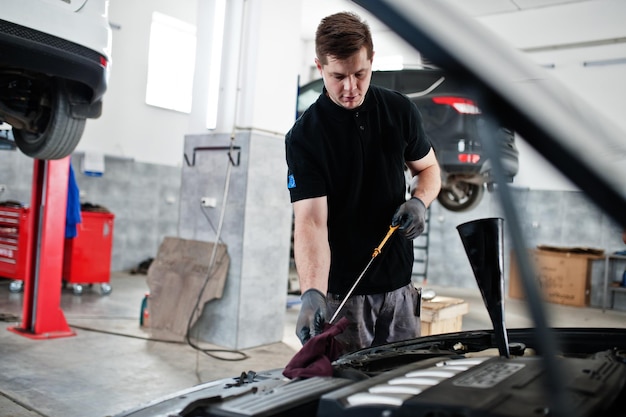 Tema de reparación y mantenimiento de automóviles Mecánico en uniforme trabajando en motor de control de servicio automático