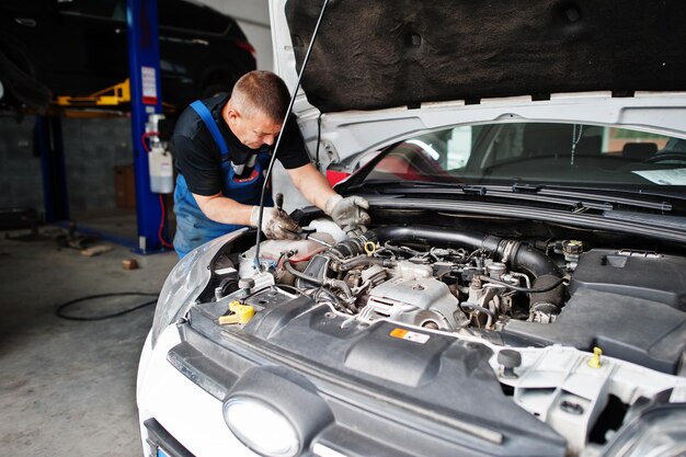 Tema de reparación y mantenimiento de automóviles Mecánico en uniforme trabajando en motor de control de servicio automático