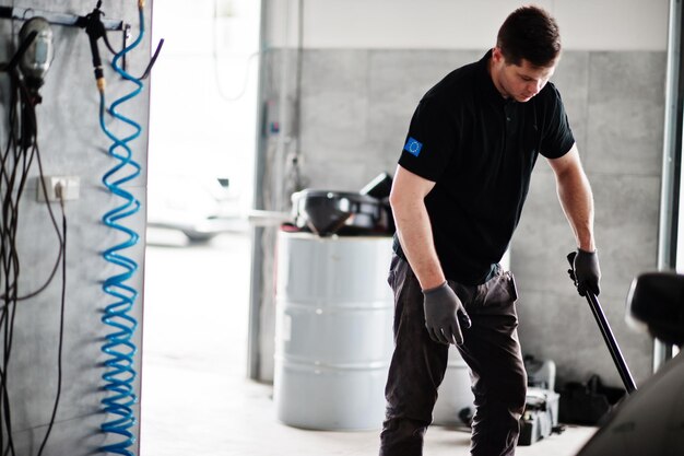 Tema de reparación y mantenimiento de automóviles Mecánico en uniforme trabajando en servicio automático