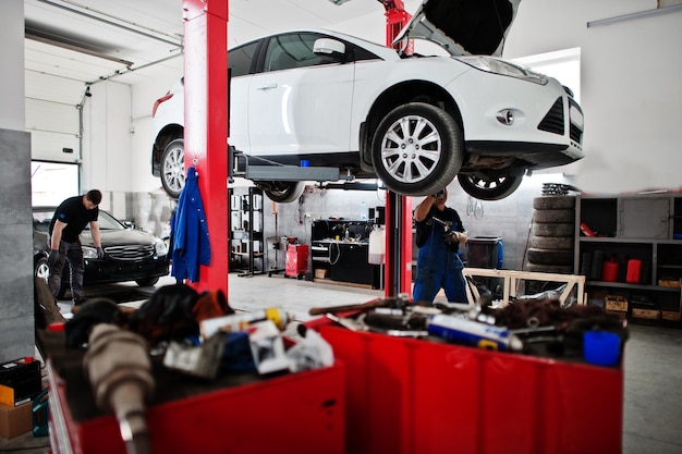 Tema de reparación y mantenimiento de automóviles Mecánico en uniforme trabajando en servicio automático