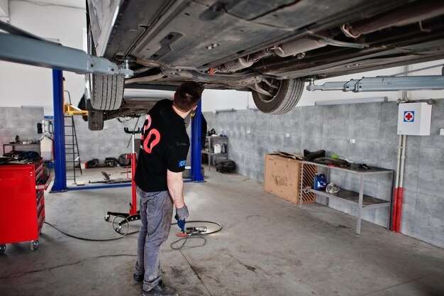 Tema de reparación y mantenimiento de automóviles Mecánico en uniforme trabajando en servicio automático