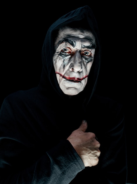 Tema sangriento de Halloween: la cara de maníaco loco en estudio oscuro