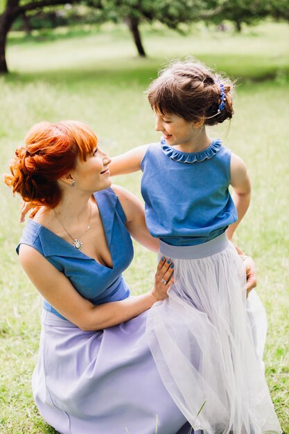 Tender abrazos de hermosa madre e hija posando en el parque