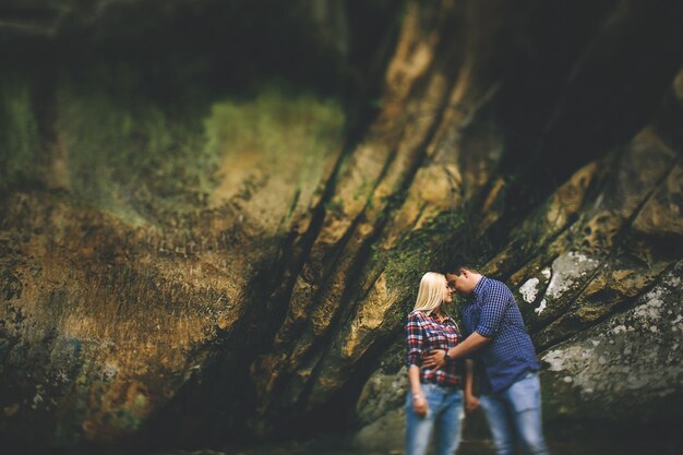 Tender abrazos de una pareja de pie bajo las rocas