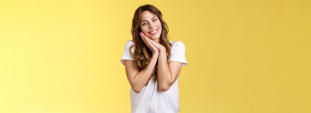 Foto gratuita tender femenina linda mujer encantadora peinado rizado inclinación de la cabeza la cara las palmas de las manos encantadas sonriendo ampliamente