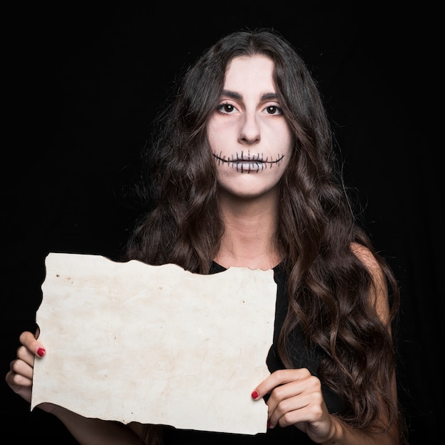 Foto gratuita tenebrosa mujer sosteniendo papel