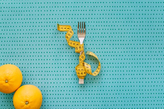 Tenedor, cinta métrica y naranjas
