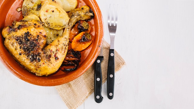 Tenedor y cuchillo cerca de deliciosa pierna de pollo