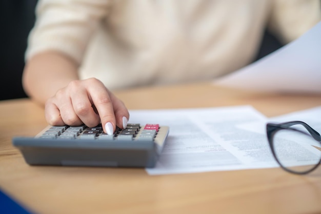 Tenedor de libros que calcula el presupuesto financiero en el escritorio de oficina