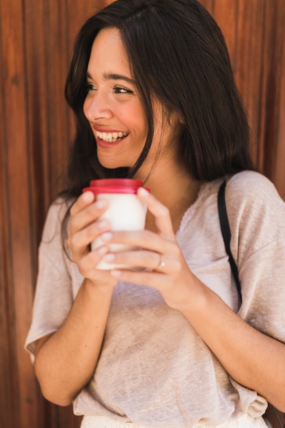 La tenencia sonriente de la muchacha se lleva la taza de café