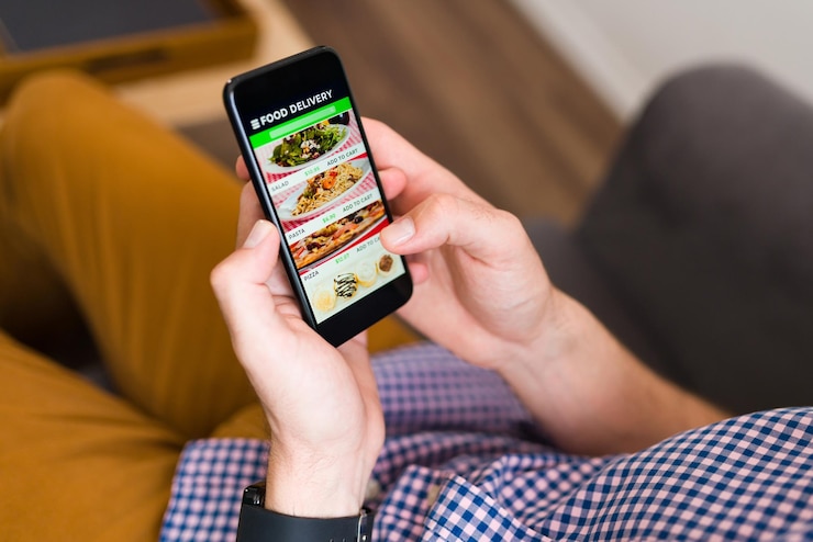 Foto gratuito tengo hambre. manos de un hombre que mira una aplicación de entrega de alimentos en su teléfono inteligente y ordena la cena en línea