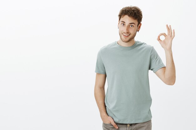 Tengo todo bajo control. Retrato de hombre guapo positivo en traje casual, levantando la mano con gesto bien o bien