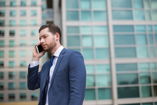 Tensed hombre de negocios hablando por teléfono al aire libre