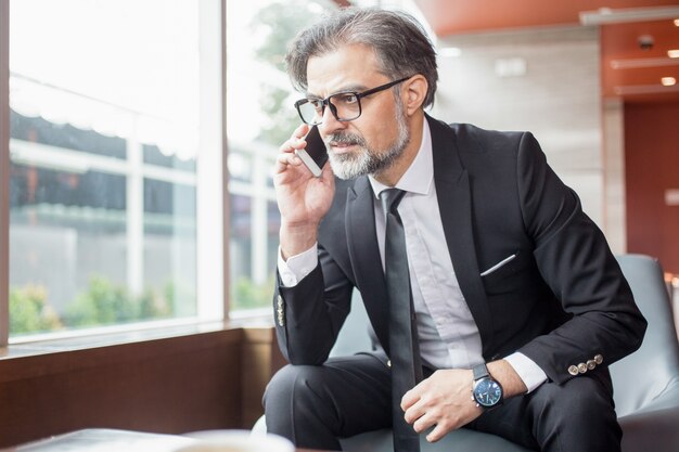 Tensed hombre de negocios hablando en el teléfono inteligente en el vestíbulo