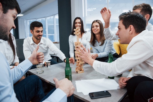 La tensión está en el aire. Celebrando el trato exitoso. Jóvenes oficinistas sentados cerca de la mesa con alcohol