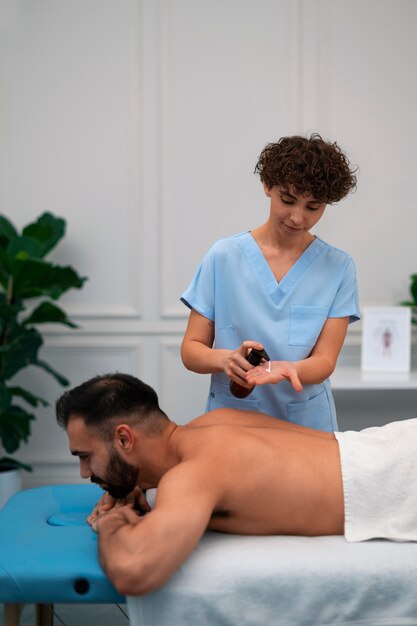 Terapeuta femenina en el centro de rehabilitación dando masaje de espalda