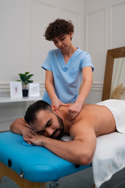Terapeuta femenina en el centro de rehabilitación dando masaje de espalda