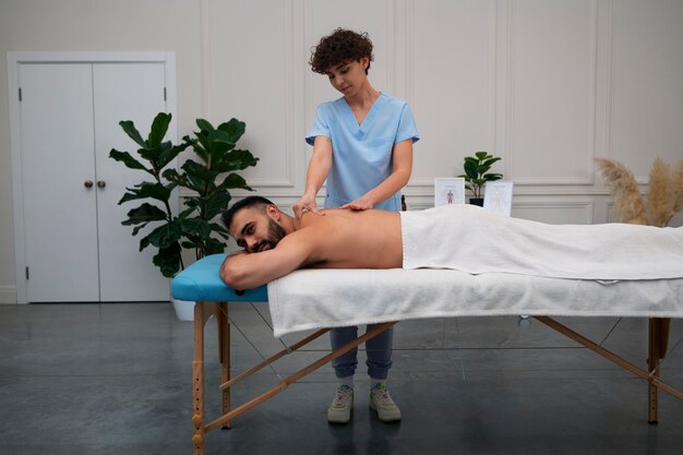 Terapeuta femenina en el centro de rehabilitación dando masaje de espalda