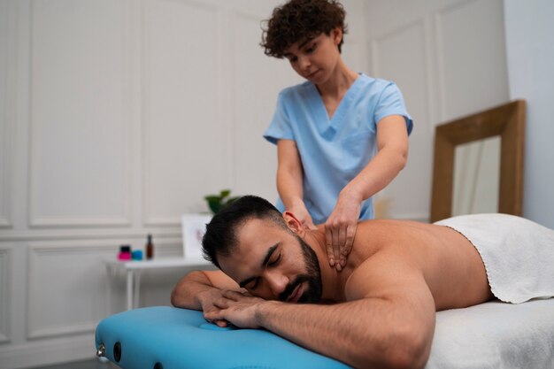 Terapeuta femenina en el centro de rehabilitación dando masaje de espalda